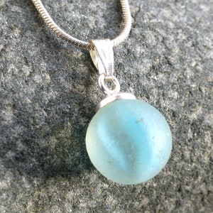 Pendant made of light sea glass ball with light blue inclusions and 925 silver loop