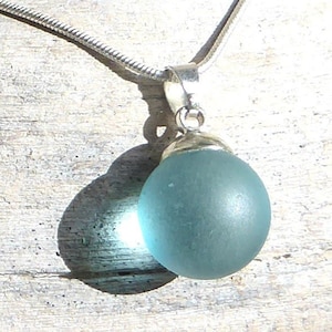 Pendant made of light green sea glass ball with silver-colored loop