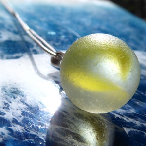 Pendant made of light sea glass ball with yellow inclusions and 925 silver loop