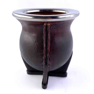 May include: A brown leather mate gourd with a silver metal rim and three legs.