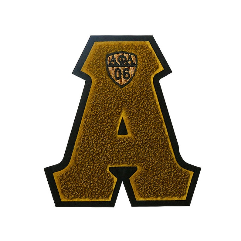 May include: A large, gold felt letter A with a black outline. The letter has a small, gold embroidered shield with the text "APA" and the number "06" inside.