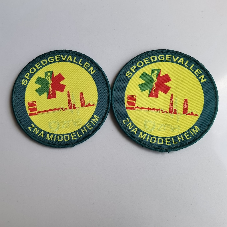 May include: Two green and yellow round patches with the text "SPOEDGEVALLEN ZNA MIDDELHEIM" and a red star of life symbol.
