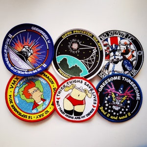 May include: Six embroidered patches with various designs and text. The patches are circular and feature a variety of colors, including red, blue, green, yellow, and black. The text on the patches includes phrases like "Geekweek V", "Thick Thighs Save Lives", and "Greesome Threesome".