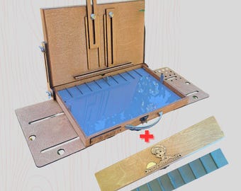 May include: A wooden artist's paint box with a blue interior and a handle. The box is open, revealing a compartment for paints and a built-in easel. Includes a separate wooden palette and a paint tray.