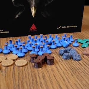 Może przedstawiać: Zbiór elementów gry do gry planszowej. Elementy obejmują niebieskie butelki z eliksirem, brązowe drewniane kłody, szare kamienie oraz zielone i brązowe elementy roślin. Są też złote monety.