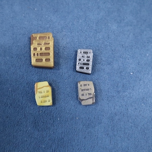 May include: Four small ceramic tiles with a grid pattern. The tiles are in shades of brown, yellow, and gray.