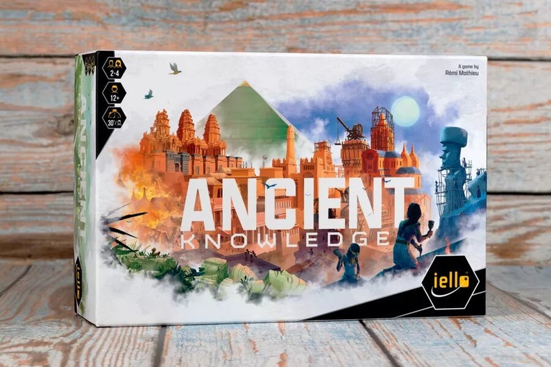 May include: A board game box with a white background and a colorful illustration of ancient buildings and structures. The title of the game is "ANCIENT KNOWLEDGE" in white letters. The game is for 2-4 players, ages 12+, and takes 30-60 minutes to play. The box is from the publisher iello.