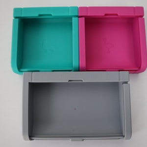 Puede incluir: Tres contenedores de almacenamiento de pl&aacute;stico apilables con tapas. El contenedor superior es de color turquesa, el contenedor del medio es de color rosa y el contenedor inferior es de color gris.