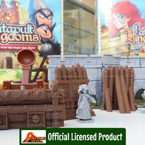 Puede incluir: Un primer plano de un conjunto de asedio de catapulta en miniatura para el juego de mesa Catapult Kingdoms. El conjunto incluye una catapulta, una pared y una figura de un guerrero. El conjunto está hecho de plástico y está pintado en marrón, gris y blanco.