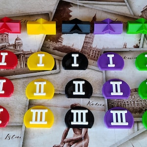 May include: A set of 36 colorful game pieces, including 12 orange, 12 red, 12 yellow, 3 black, 3 purple, 3 green, and 3 blue pieces. Each piece has a Roman numeral I, II, or III on it.