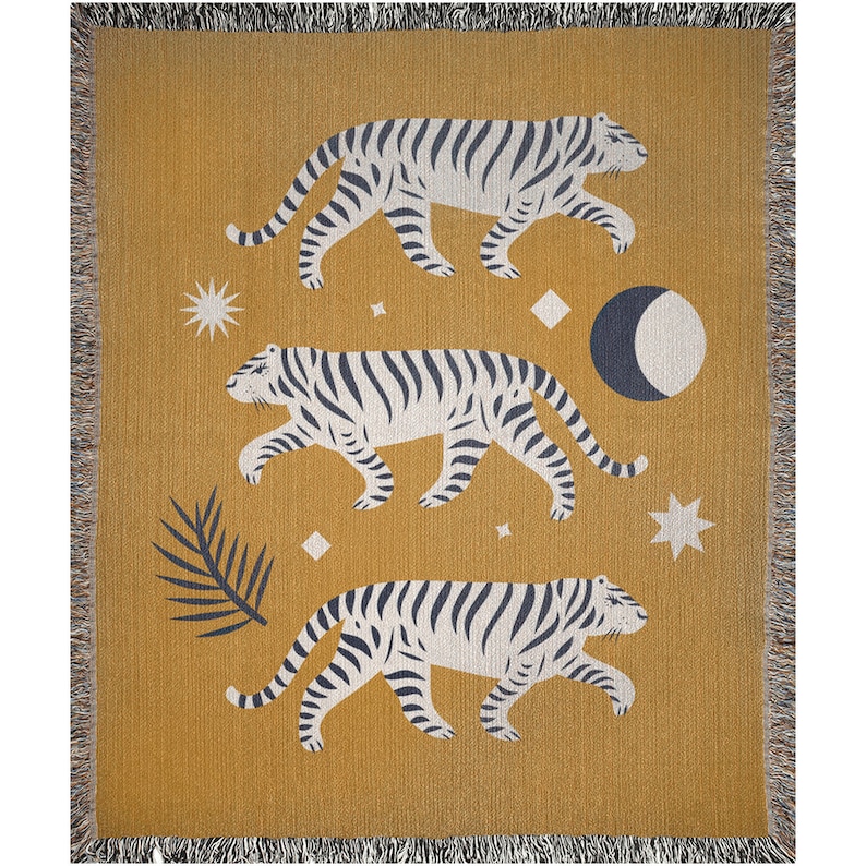 May include: A mustard yellow woven throw blanket with a white and black striped tiger design. The blanket features three tigers walking across the fabric with a moon and stars in the background.