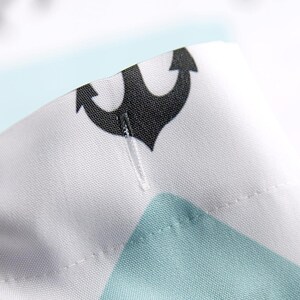 A close-up view of a fabric with a black anchor symbol on it, along with a small white thread or needle.
