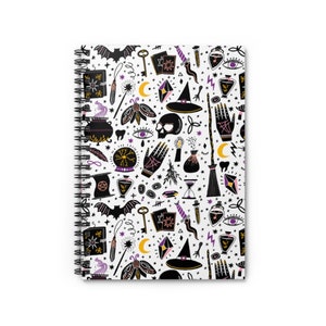 May include: A white spiral notebook with a black and purple pattern of witchy symbols, including a cauldron, a skull, a wand, a broom, a crescent moon, a crystal ball, and a witch's hat.