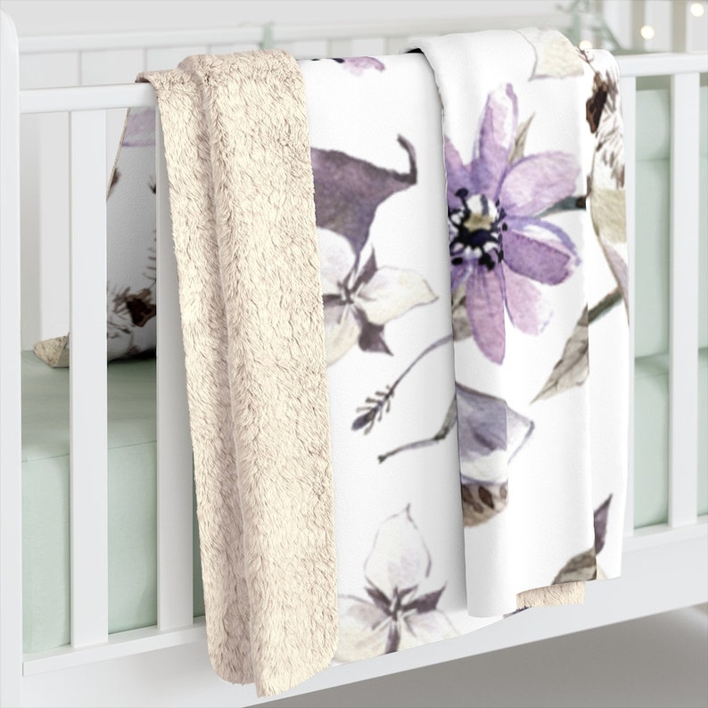 May include: A white and purple floral patterned throw blanket with a soft, cream-colored sherpa backing.