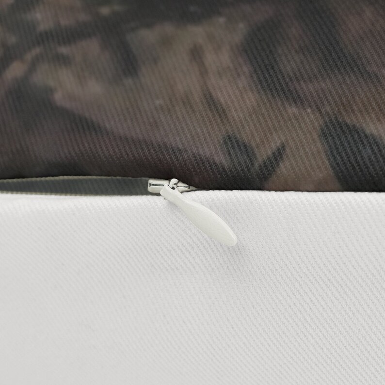 May include: Close-up of a zipper on a white pillowcase. The zipper is silver and has a white pull tab. The pillowcase is made of a soft, white fabric.