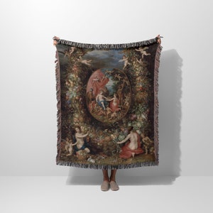 May include: A woven tapestry throw blanket featuring a Renaissance-style painting of a garden scene with figures and fruit. The tapestry is framed with a fringe border.