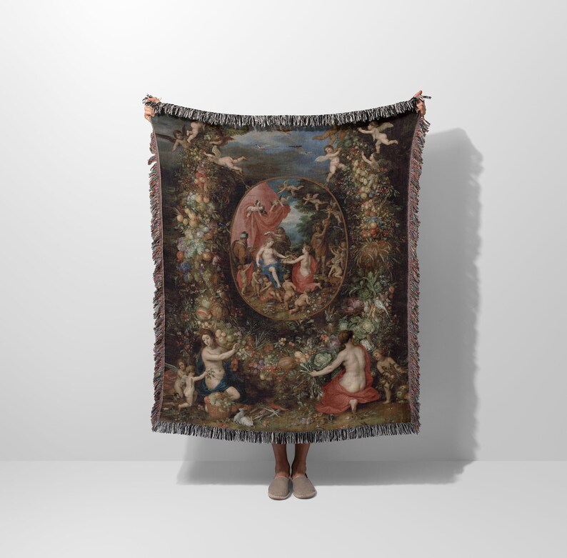 May include: A woven tapestry throw blanket featuring a Renaissance-style painting of a garden scene with figures and fruit. The tapestry is framed with a fringe border.