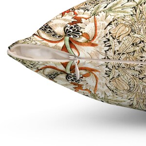 May include: A cream-colored pillow with a zipper closure. The pillow features a floral pattern with orange, brown, and green accents.