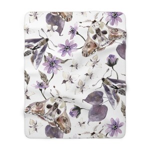 May include: A white background with a repeating pattern of purple flowers, leaves, and moths. The moths have a skull and crossbones design on their wings.