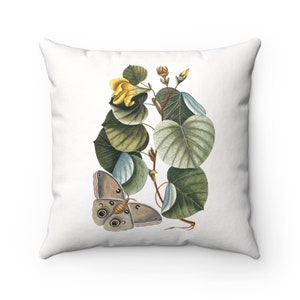 May include: A white throw pillow featuring a botanical illustration of a butterfly and a yellow flower with green leaves.