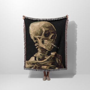 a woman standing in front of a wall holding a blanket with a painting of a