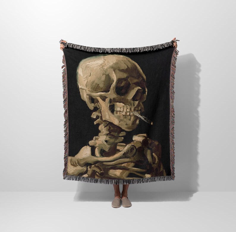 a woman standing in front of a wall holding a blanket with a painting of a