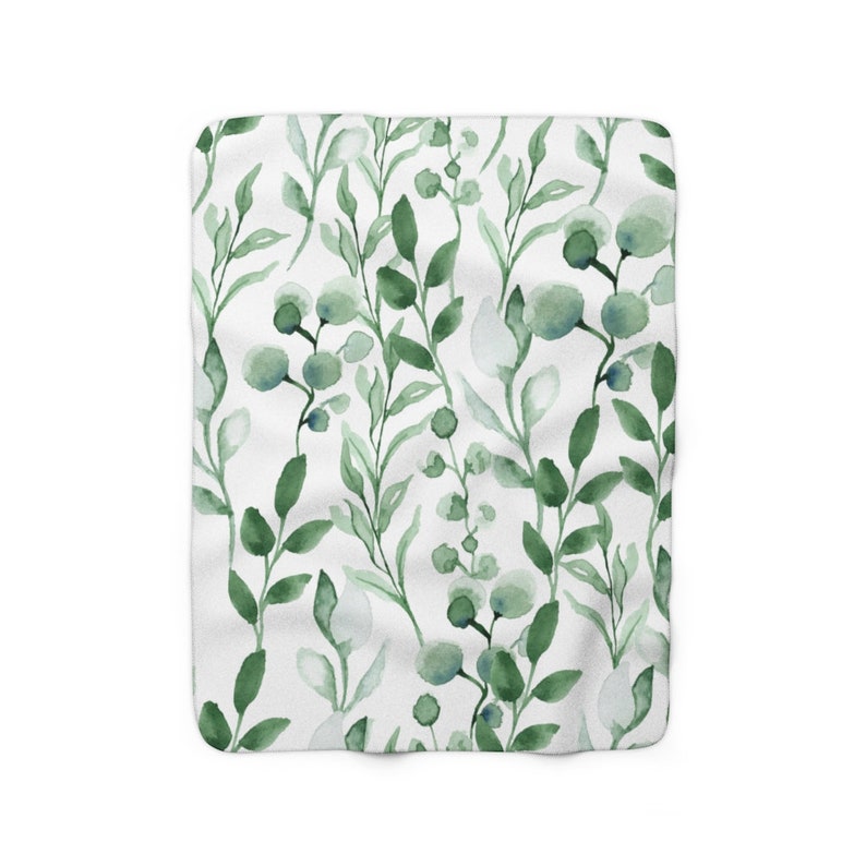 Puede incluir: Una manta blanca con un patr&oacute;n floral verde en acuarela. El patr&oacute;n presenta hojas y peque&ntilde;os c&iacute;rculos verdes.