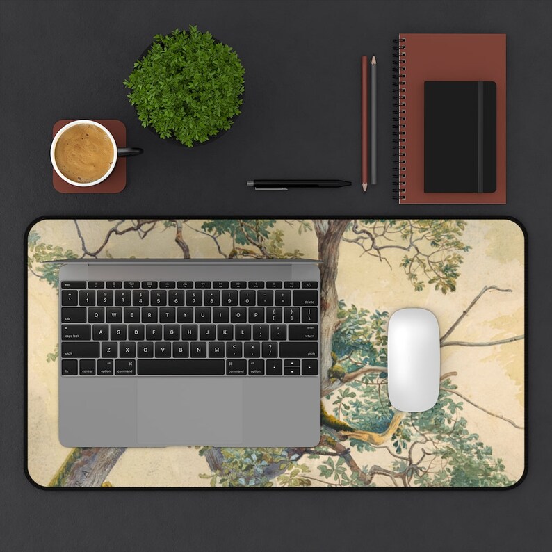 May include: A laptop computer, a wireless mouse, and a cup of coffee are on a desk mat with a watercolor design of a tree with green leaves.