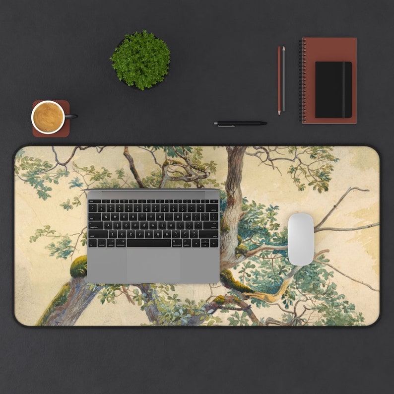 May include: A desk mat with a watercolor painting of a tree with green leaves and brown branches on a beige background. A laptop computer and a white mouse are on the desk mat.