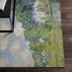 May include: A rectangular rug with a painting of a landscape scene. The rug features a blue sky with white clouds, green trees, and a river. The rug has a light blue, green, and yellow color scheme.