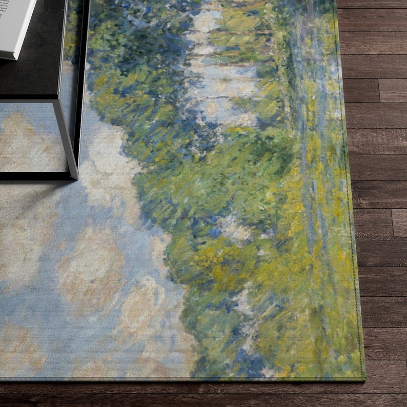 May include: A rectangular rug with a painting of a landscape scene. The rug features a blue sky with white clouds, green trees, and a river. The rug has a light blue, green, and yellow color scheme.