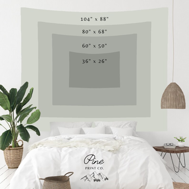 May include: A white bed with a white duvet cover and a white throw blanket. The bed is in front of a white wall with a green tapestry hanging on it. The tapestry has four rectangular frames with the dimensions 104" x 88", 80" x 68", 60" x 50", and 36" x 26" printed on them. The tapestry also has the text "Pine PRINT CO." printed on it.