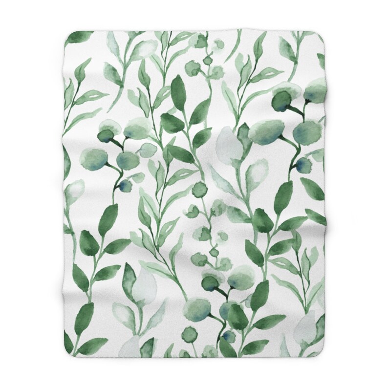 Puede incluir: Una manta blanca con un patr&oacute;n floral de acuarela verde. El patr&oacute;n presenta hojas y peque&ntilde;as flores.