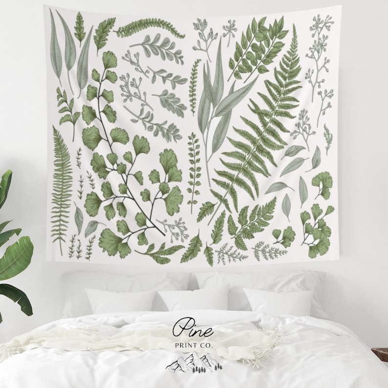 May include: A white tapestry with a green botanical print featuring various types of leaves and ferns. The tapestry has a white background with a green floral pattern.