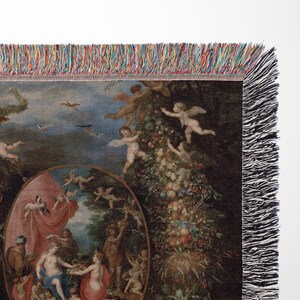 May include: A woven tapestry throw blanket featuring a colorful Renaissance-style painting of a group of people in a garden setting. The painting is surrounded by a border of cherubs and fruit.