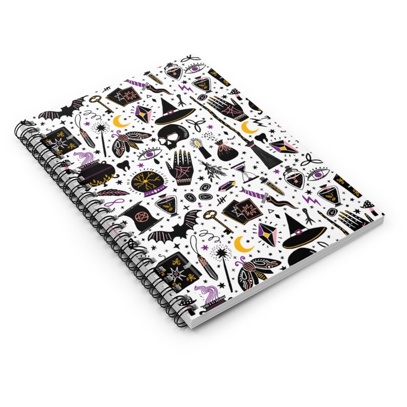 May include: A white spiral notebook with a black and white pattern of witchy symbols and objects. The pattern includes a witch's hat, a cauldron, a wand, a crystal ball, a crescent moon, a bat, a key, a skull, a potion bottle, a hand with an eye, a broom, and a book. The notebook is perfect for taking notes, writing down spells, or journaling.