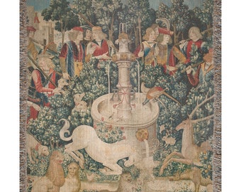 May include: A tapestry depicting a unicorn being captured by hunters in a forest setting. The unicorn is white and is being led by a rope to a fountain. The hunters are dressed in medieval clothing and are surrounded by trees and other animals.