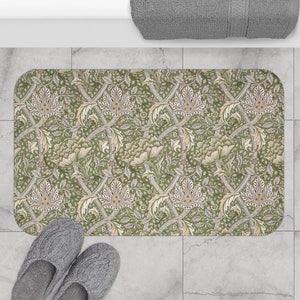 May include: A green and cream bath mat with a floral pattern. The pattern features stylised flowers and leaves in a repeating design.
