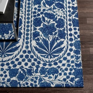 May include: A blue and white floral patterned rug. The rug features a repeating design of stylized flowers and leaves in a deep blue color against a white background. The rug is rectangular and appears to be made of a woven material.