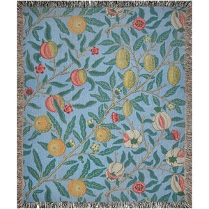 May include: A woven throw blanket with a blue background and a repeating pattern of lemons, oranges, and flowers. The pattern is in shades of green, yellow, orange, and pink.