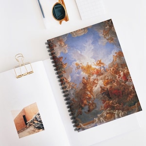 May include: A spiral bound notebook featuring a colourful painting of a ceiling fresco. The painting depicts a scene of angels and clouds in a blue sky.