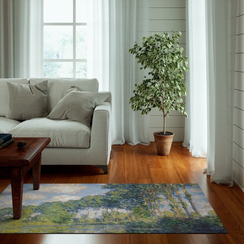 May include: A living room with a white couch, a coffee table, a potted plant, and a rug with a painting of trees and water. The rug is a light blue, green, and yellow color.