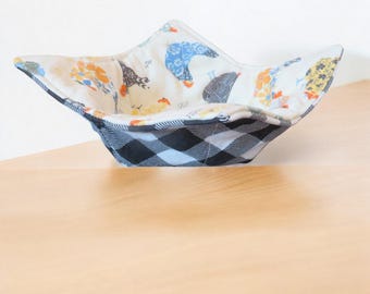 May include: A white fabric bowl with a black and white checkered pattern on the outside. The inside of the bowl is lined with a white fabric with a colorful chicken print.