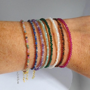 Peut inclure: Un ensemble de huit bracelets de perles délicats composés de petites pierres précieuses à facettes dans des tons rose, bleu, violet, vert clair, vert foncé, blanc, marron et magenta, chacun doté d'une fine chaîne en métal doré ou argenté.