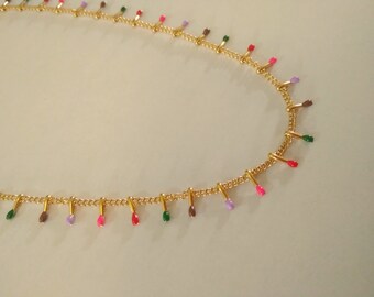 Short necklace, or choker, women's chain with multi-colored pendants, multiple steel tassels in gold color