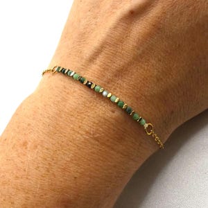 Peut inclure: Un bracelet délicat en chaîne dorée avec des perles vertes et noires. Le bracelet a un design simple et est parfait pour tous les jours.