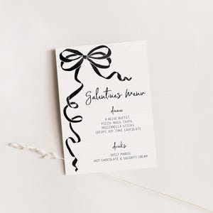 Könnte beinhalten: Eine cremefarbene Galentine's-Menükarte mit schwarzer Schrift und einem dekorativen Schleifen- und Banddesign. Die Speisekarte listet Abendessen wie Pizza, Nuggets und Pommes sowie Getränke wie scharfe Margaritas und heiße Schokolade auf.