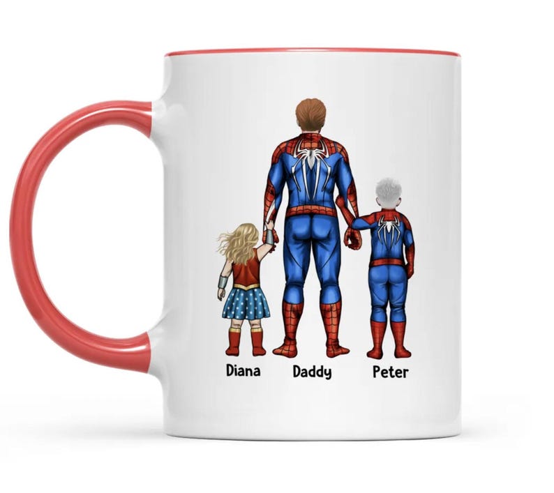 May include: White ceramic mug with a red interior and handle. The mug features a graphic of a family dressed as superheroes: Spider-Man, Wonder Woman, and a child in a Spider-Man suit. The names "Diana", "Daddy", and "Peter" are printed below the characters.