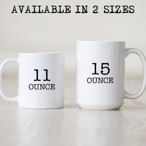 May include: Two white ceramic mugs, one smaller and one larger, with black text indicating sizes. The smaller mug reads "11 OUNCE" and the larger mug reads "15 OUNCE". The text "AVAILABLE IN 2 SIZES" is printed above the mugs.