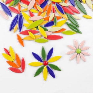 May include: A collection of brightly coloured, leaf-shaped ceramic tiles. The tiles are in shades of red, orange, yellow, green, blue, and pink. Some are arranged in flower patterns, others scattered on a white background.